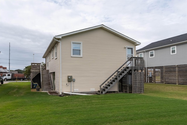rear view of house with stairs, a lawn, and fence