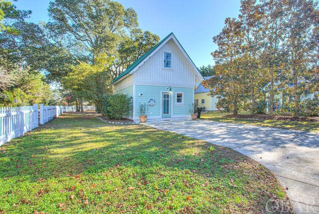 view of front of property with board and batten siding, a front yard, and fence