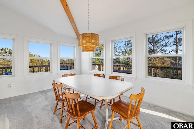 carpeted dining area featuring lofted ceiling with beams, baseboards, and a chandelier