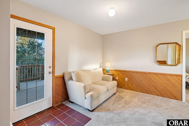 sitting room with wooden walls, wainscoting, and dark carpet