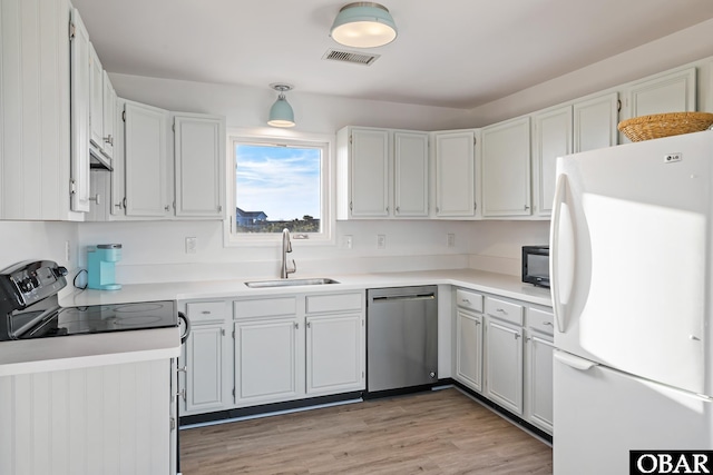 kitchen featuring visible vents, light wood-style flooring, a sink, black appliances, and light countertops