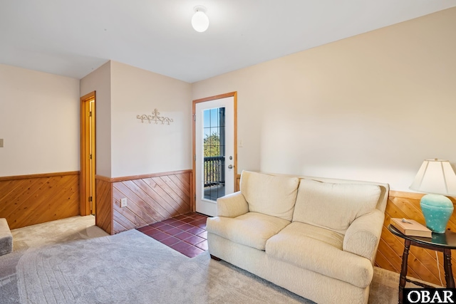 carpeted living room with a wainscoted wall and wood walls