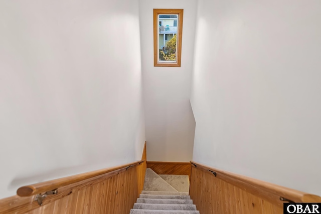 stairs with wood walls and wainscoting