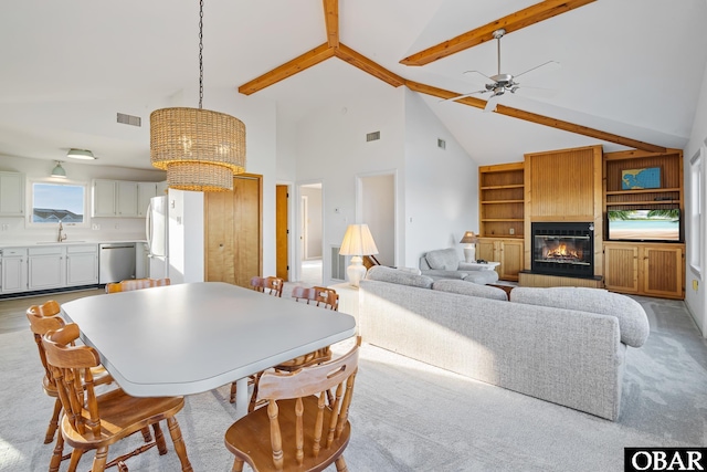 dining space featuring visible vents, a fireplace, vaulted ceiling with beams, and ceiling fan