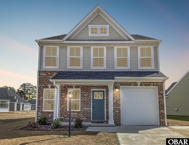 view of front of house with brick siding, roof with shingles, and driveway