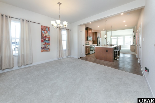 kitchen with a kitchen island with sink, appliances with stainless steel finishes, and dark colored carpet