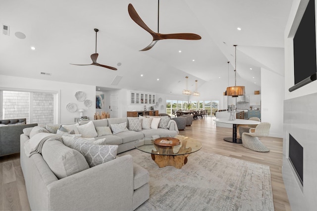 living room with recessed lighting, visible vents, light wood-style flooring, ceiling fan, and high vaulted ceiling