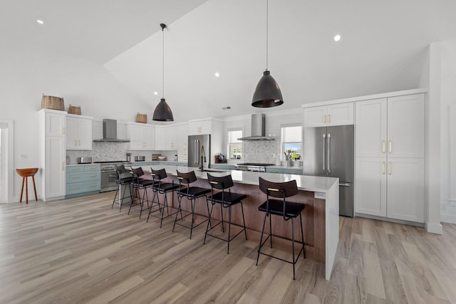 kitchen featuring wall chimney exhaust hood, white cabinetry, stainless steel appliances, and light countertops