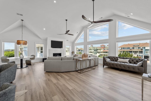 living room featuring light wood-style floors, plenty of natural light, a fireplace, and ceiling fan