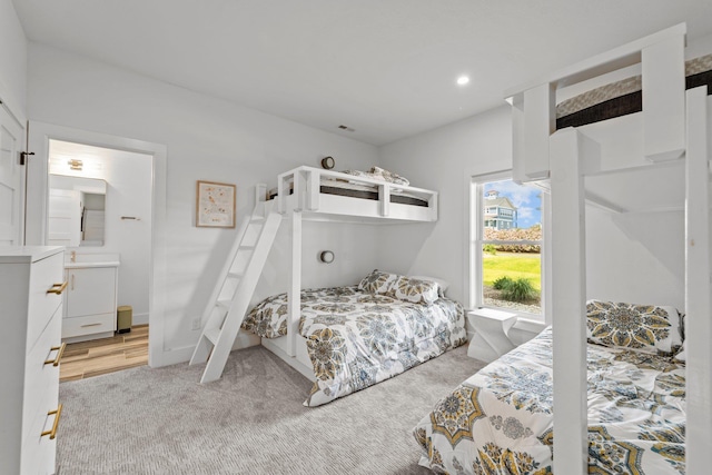 bedroom with recessed lighting, light colored carpet, visible vents, baseboards, and ensuite bath