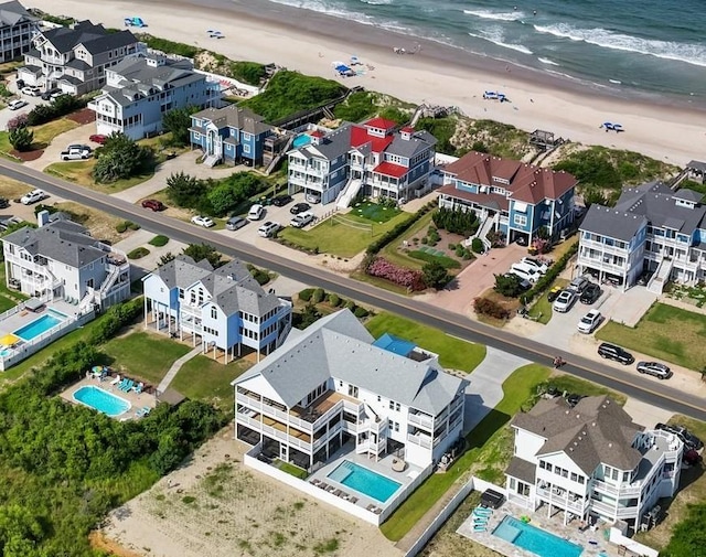 drone / aerial view featuring a water view, a residential view, and a view of the beach