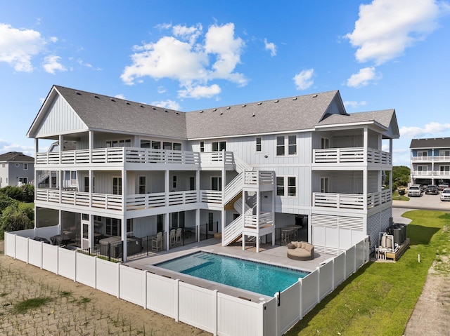 back of house featuring roof with shingles, board and batten siding, a patio area, central AC, and an outdoor pool