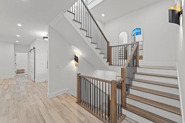 staircase featuring recessed lighting, wood finished floors, baseboards, and a barn door