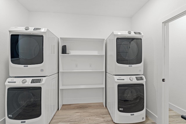 laundry room with baseboards, laundry area, light wood-style floors, and stacked washer / drying machine