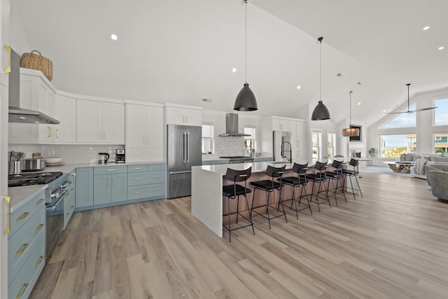 kitchen with premium appliances, open floor plan, range hood, light countertops, and white cabinetry