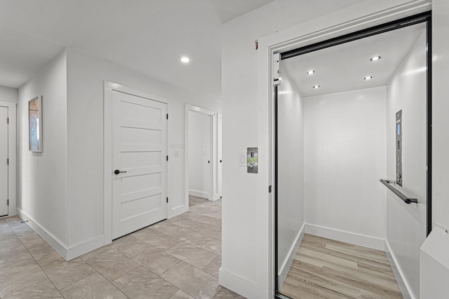 hall featuring baseboards, recessed lighting, and elevator