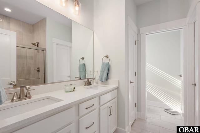 full bath featuring double vanity, a sink, and a shower stall