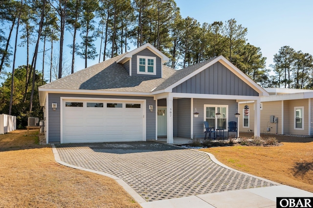 view of front of house with a garage, driveway, a shingled roof, covered porch, and board and batten siding