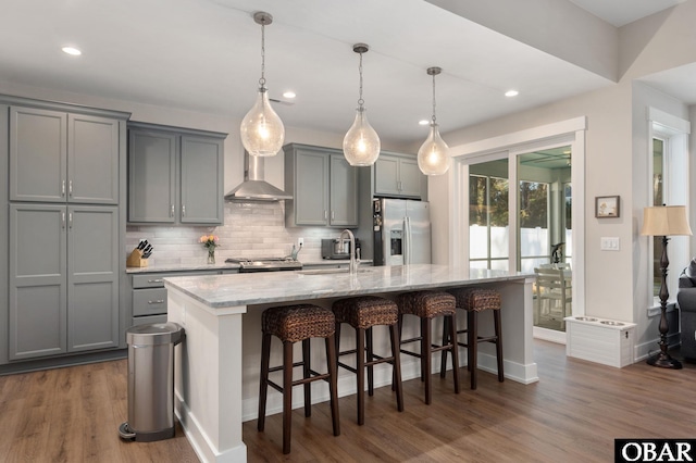 kitchen featuring gray cabinets, a sink, wall chimney range hood, and stainless steel fridge with ice dispenser