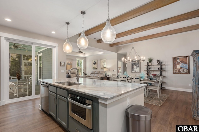 kitchen with stainless steel appliances, a sink, open floor plan, gray cabinets, and dark wood-style floors