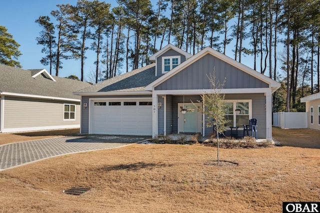 view of front of house featuring a garage, driveway, roof with shingles, covered porch, and board and batten siding