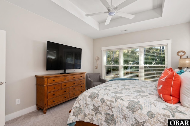 carpeted bedroom with a ceiling fan, a tray ceiling, visible vents, and baseboards