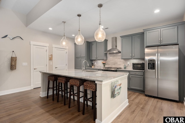 kitchen with stainless steel fridge, wall chimney exhaust hood, gray cabinets, black microwave, and a sink