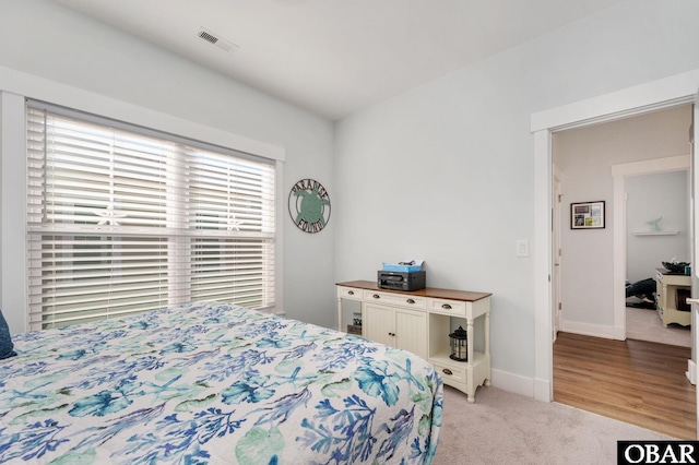 bedroom with light colored carpet, visible vents, and baseboards