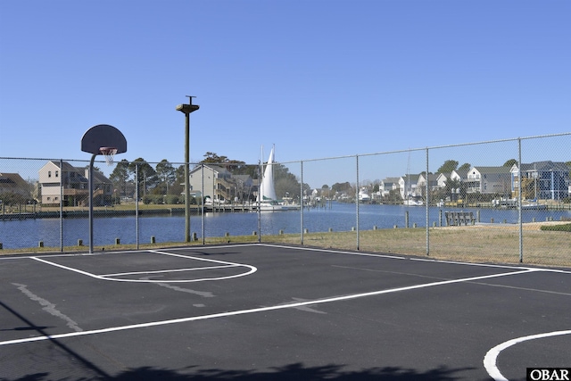 view of basketball court featuring a residential view, a water view, community basketball court, and fence