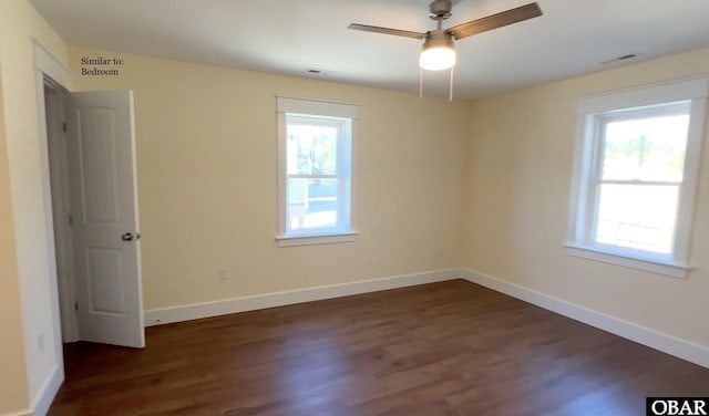 empty room with dark wood-style floors, visible vents, plenty of natural light, and baseboards