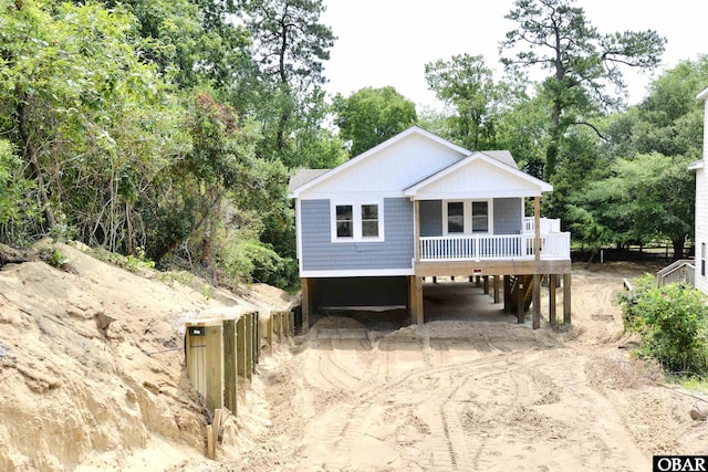 112 Mybet Ct Lot 100, Kill Devil Hills, NC 27948 - view of front of house featuring a carport, dirt driveway, covered porch, and view of scattered trees