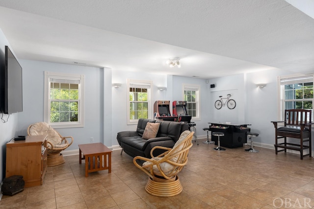 living area featuring light tile patterned floors, baseboards, and a wealth of natural light