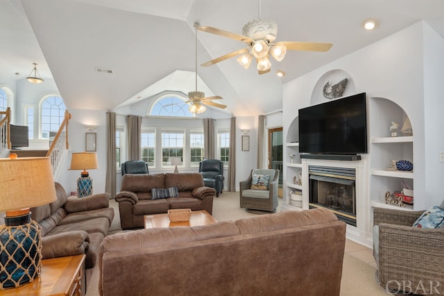 living area with light carpet, built in features, a ceiling fan, lofted ceiling, and a fireplace