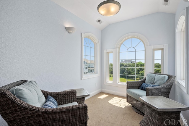 sitting room with lofted ceiling, visible vents, and carpet flooring