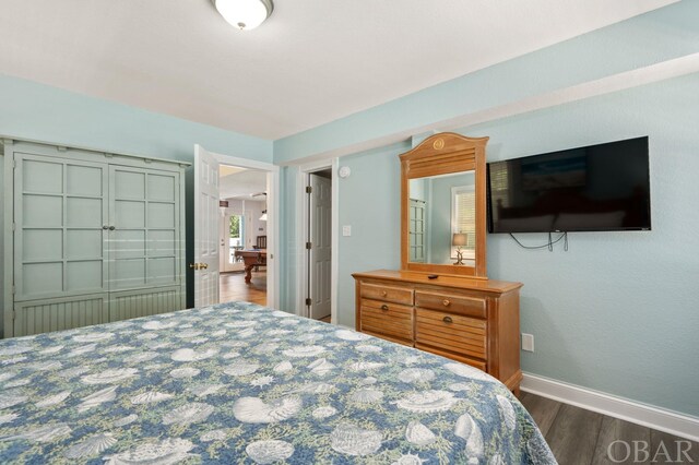 bedroom with baseboards and dark wood-type flooring