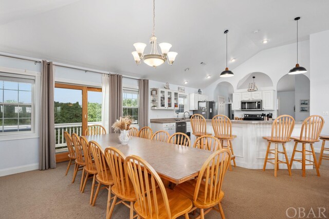 dining space featuring arched walkways, baseboards, a chandelier, and light colored carpet