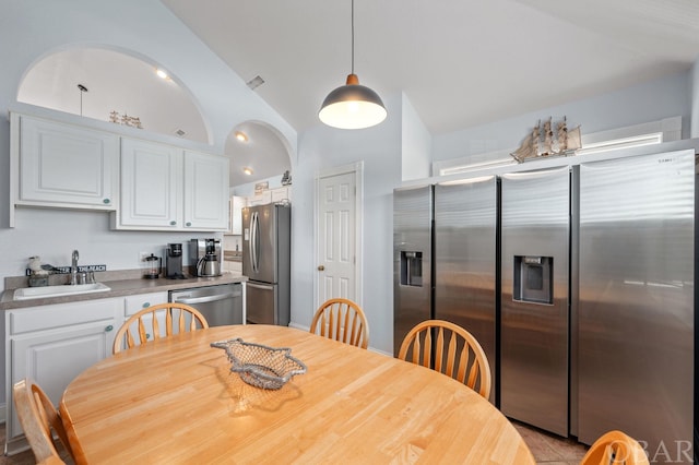 kitchen featuring appliances with stainless steel finishes, decorative light fixtures, a sink, and white cabinetry