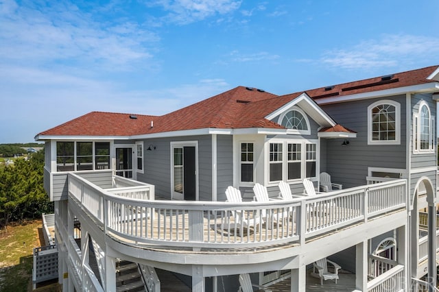 rear view of house featuring a shingled roof, stairway, and a wooden deck