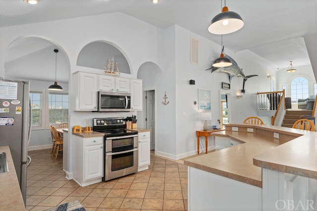 kitchen featuring pendant lighting, stainless steel appliances, light countertops, and white cabinets