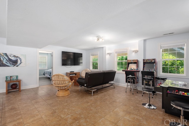 living area with baseboards, visible vents, and a healthy amount of sunlight