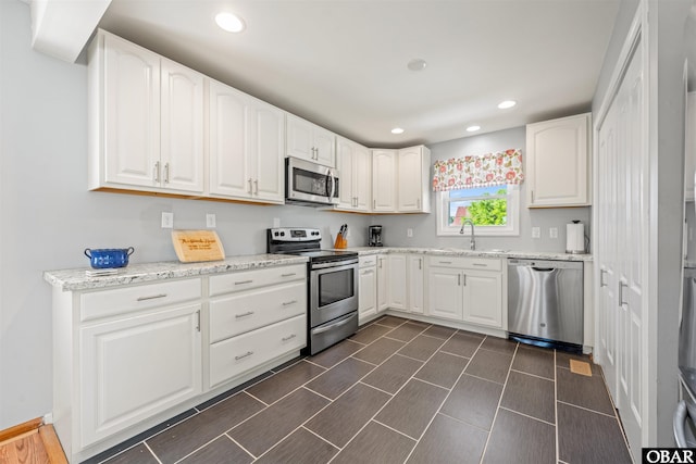 227 Outrigger Dr Lot 132, Kill Devil Hills, NC 27948 - kitchen with light stone countertops, recessed lighting, stainless steel appliances, white cabinets, and a sink