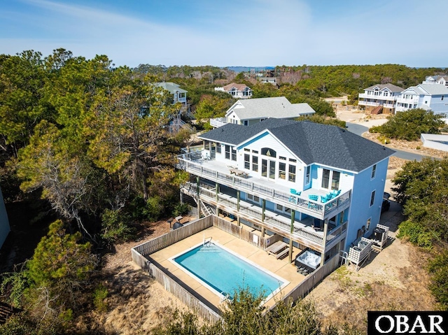 rear view of house featuring a patio, fence, roof with shingles, a fenced in pool, and a balcony