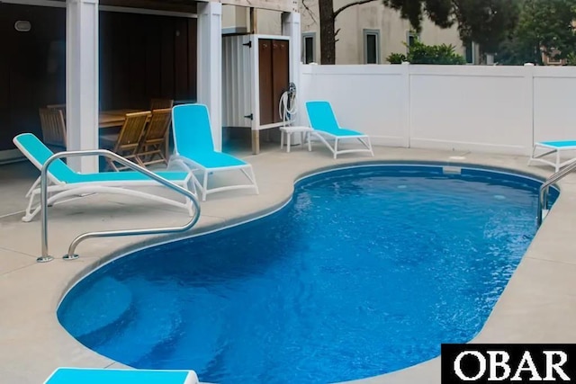 view of swimming pool featuring a patio and fence