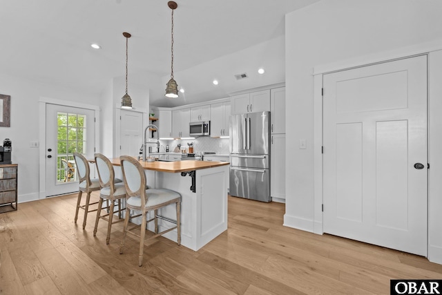 kitchen with stainless steel appliances, butcher block countertops, recessed lighting, a kitchen breakfast bar, and backsplash