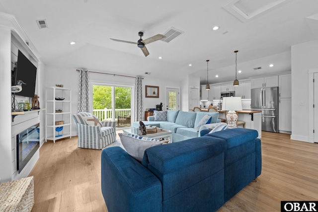 living room with light wood-style floors, ceiling fan, recessed lighting, a glass covered fireplace, and lofted ceiling