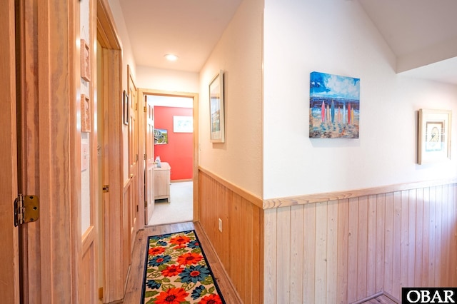 hall featuring a wainscoted wall and wooden walls