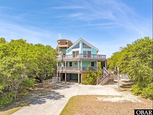coastal home featuring a carport, an attached garage, stairs, and driveway
