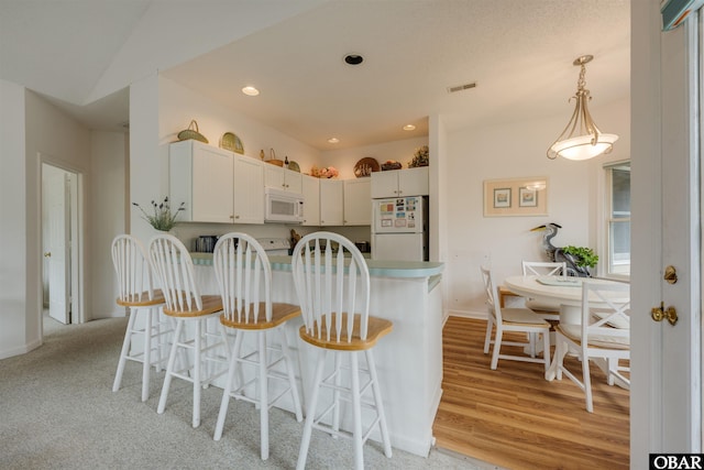 kitchen with recessed lighting, white appliances, white cabinets, light countertops, and pendant lighting