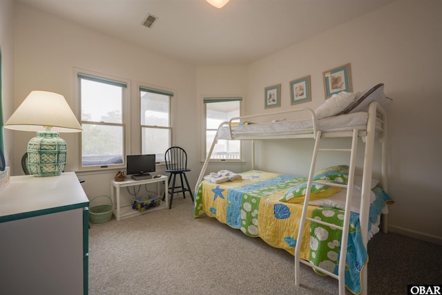 carpeted bedroom featuring visible vents, baseboards, and multiple windows