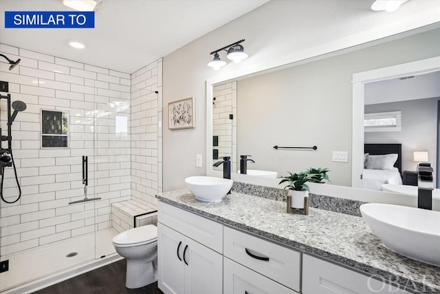 ensuite bathroom featuring ensuite bathroom, toilet, wood finished floors, vanity, and a stall shower